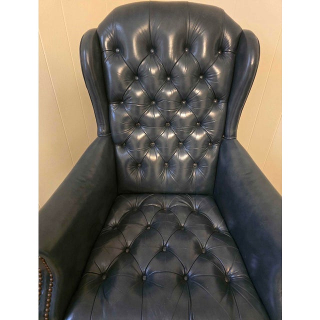 Midnight blue genuine leather, Chesterfield wingback chair. Classic deep button tufting, rolled arms, and brass nailhead...