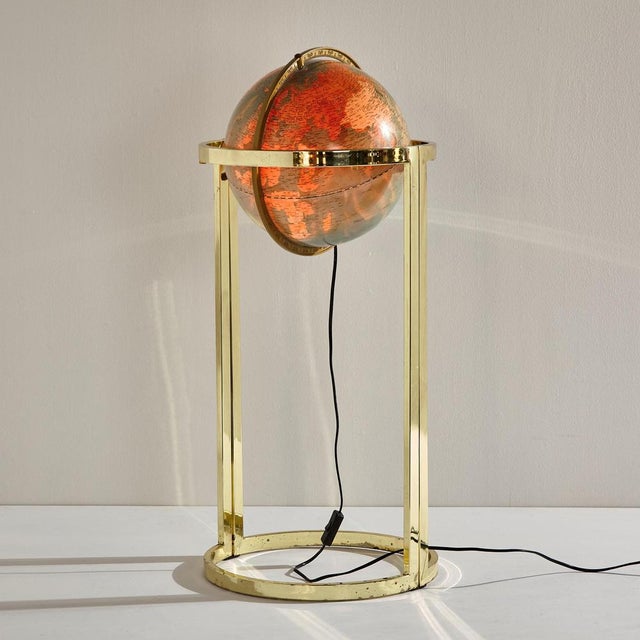 Illuminated globe on brass frame from the 1980s. with several surface scratches, wear and rust on the steel frame.