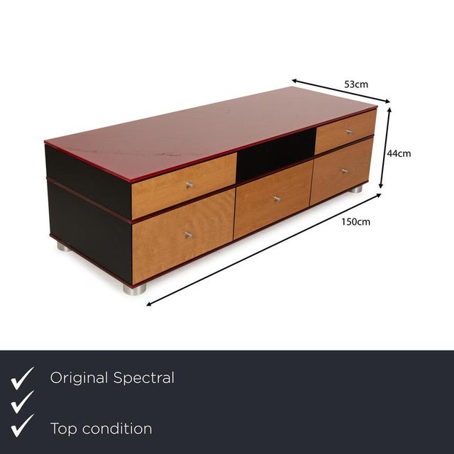 The Spectral sideboard is made of wood and glass and stands on low, round metal feet. The top shelf is made of red glass...