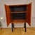A beautifully crafted mid-century modern teak cabinet featuring sleek black tapered legs and minimalistic design. This...