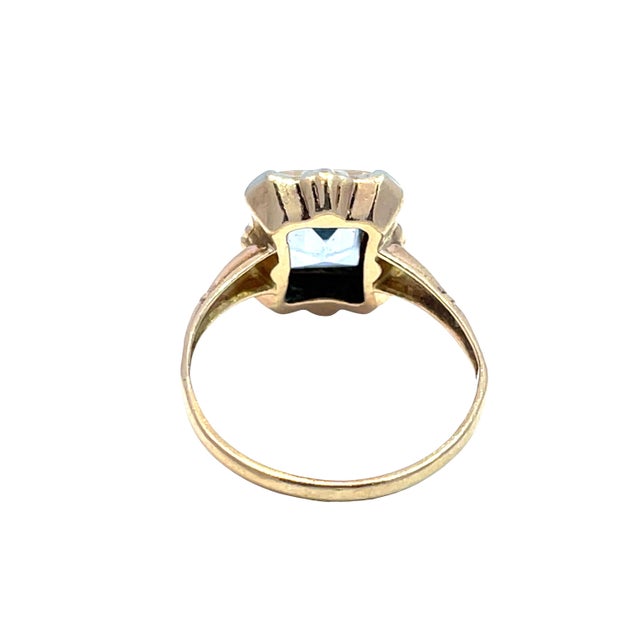 Elegant vintage ring featuring a beautifully faceted emerald-cut blue topaz set in solid two-tone gold. The refined design...