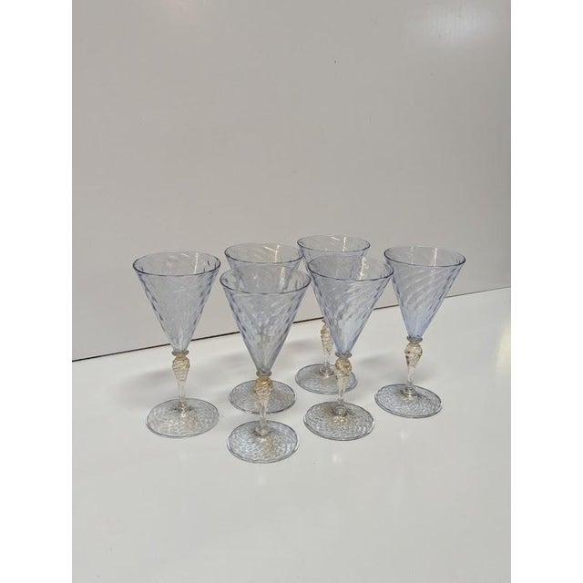 A striking matched set of six vintage Venetian Murano hand-blown wine goblets featuring luminous ice-blue conical bowls,...