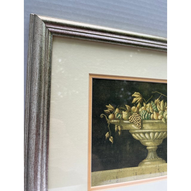 A single print of a floral still life in urn finished with a silver tone wood frame, glass, and a melon colored accent mat.