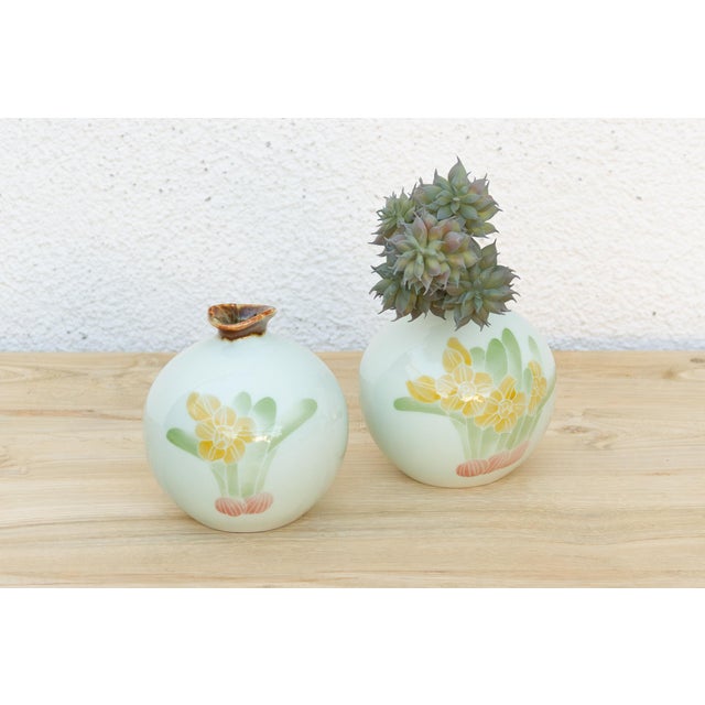 Both vases in this pair share the same pale celadon-white ground and the same hand-painted motif, small yellow narcissus...