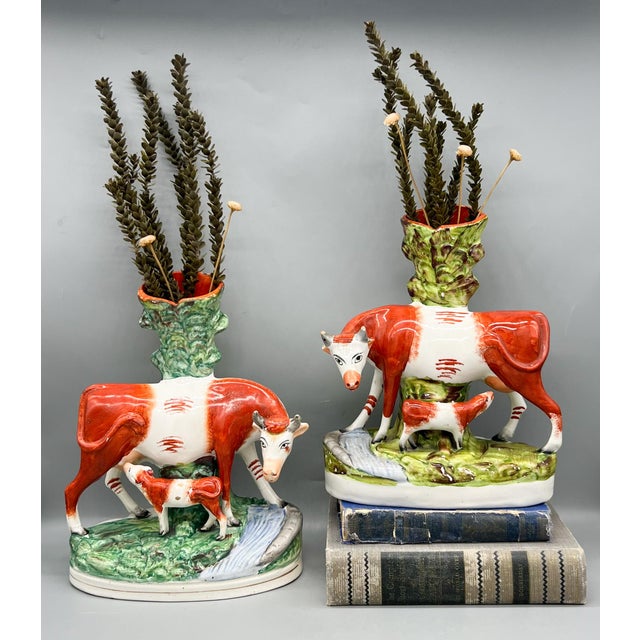 Incredible and rare pair of large Staffordshire pottery spill vases, each depicting a red-and-white cow with a nursing...