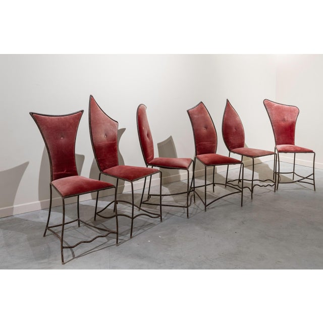 Set of six chairs made of iron with backs and seats upholstered in burgundy velvet. Each chair is unique, featuring...