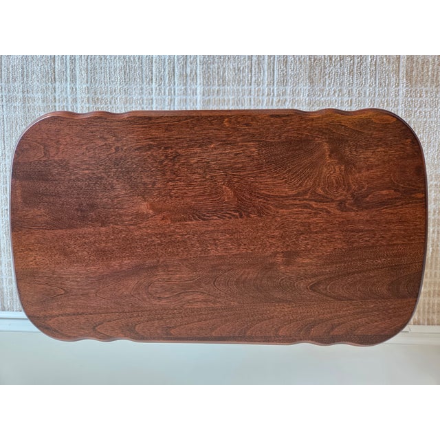This is an elegant, classically styled side table. It is designed with curves on its top, two additional shelves, and side...