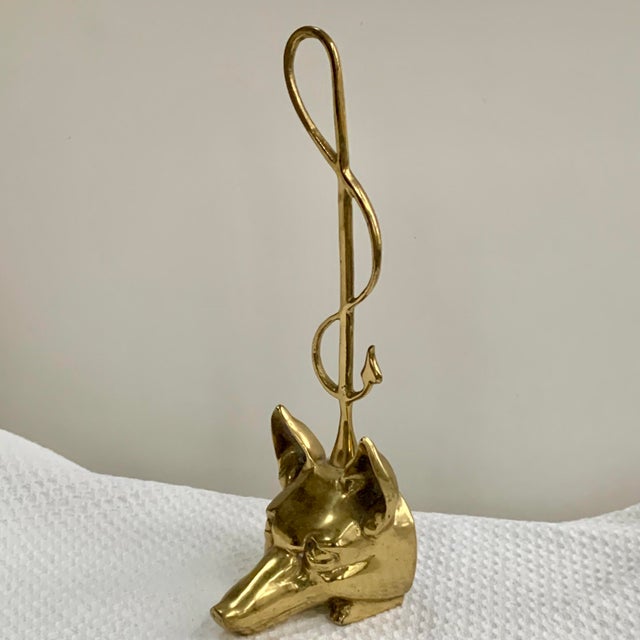 The Virginia Metalcrafters Brass Fox & Whip Door Stop is a vintage decorative accessory designed with a charming fox...