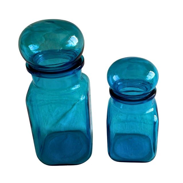A striking pair of Belgian apothecary jars in rich cobalt blue glass, dating to around 1930. Their softly rounded stoppers...