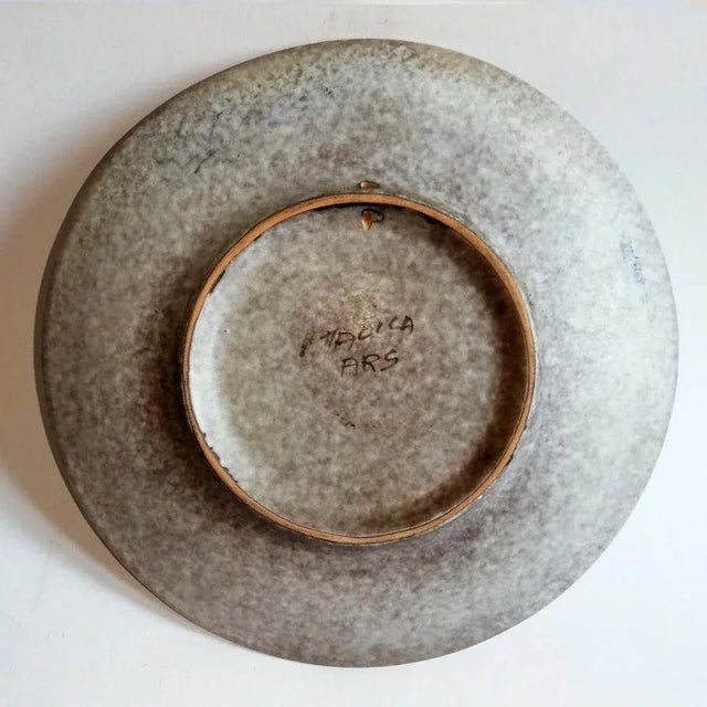 This flat ceramic wall plate depicts a landscape. It retains its Italica ARS label and is signed Lazzaro.