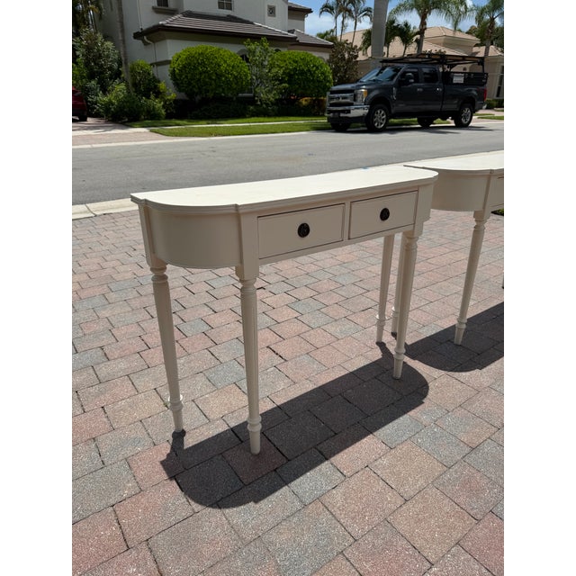 Matching pair of Somerset Bay narrow two-drawer console tables in a soft ivory-white painted finish. Curved ends, turned...