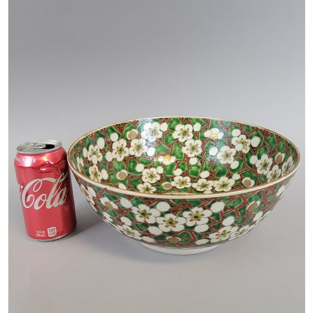 A generously scaled Japanese porcelain bowl, richly decorated in the Kutani palette with dense cherry blossom branches set...