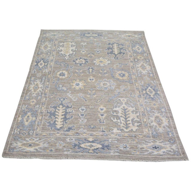A hand-knotted Turkish Oushak rug featuring soft, time-worn tones and signature large-scale motifs that bring effortless...