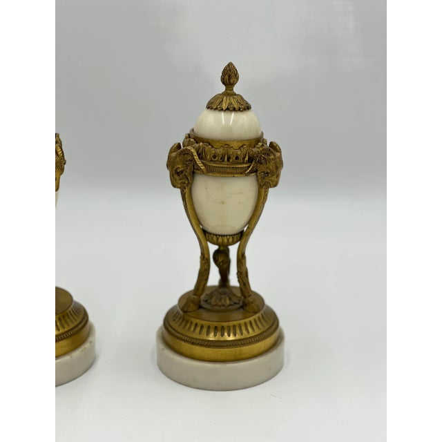 A pair of 19th century Louis XVI style gilt bronze and white marble cassolettes. Each decorated with 3 ram’s heads...