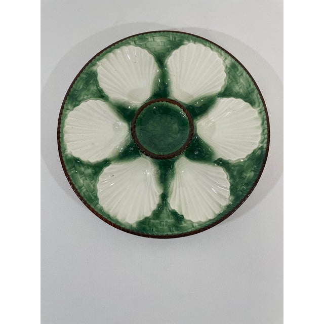A striking antique French Longchamp glazed majolica oyster plate with a vibrant green basket weave background and brown...