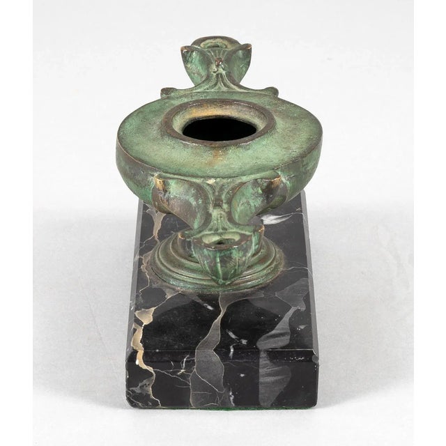 Italian Grand Tour patinated bronze double-nozzle oil lamp on a round pedestal and mounted on a black, grey and golden...