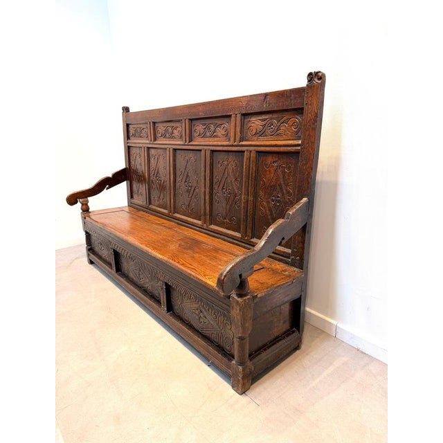 A beautiful antique solid oak monks bench featuring richly hand-carved panels and a practical lift-up seat with generous...