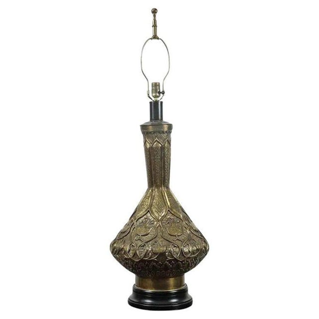 Large Indo Persian brass table lamp, finely embossed with Moorish Islamic repousse floral designs, sits on a black...