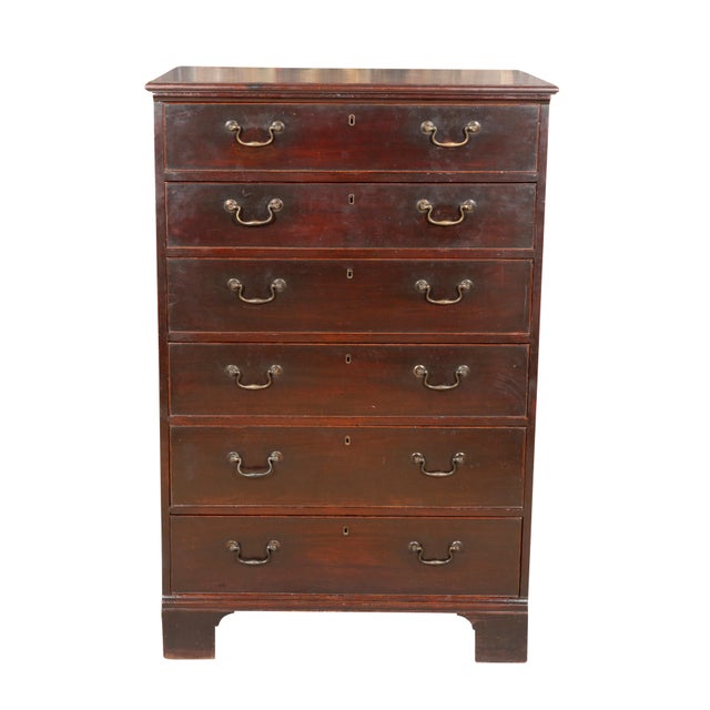 Finished rectangular top over six graduated drawers with brass bail handles. Raised on bracket feet. Old finish. Well made...