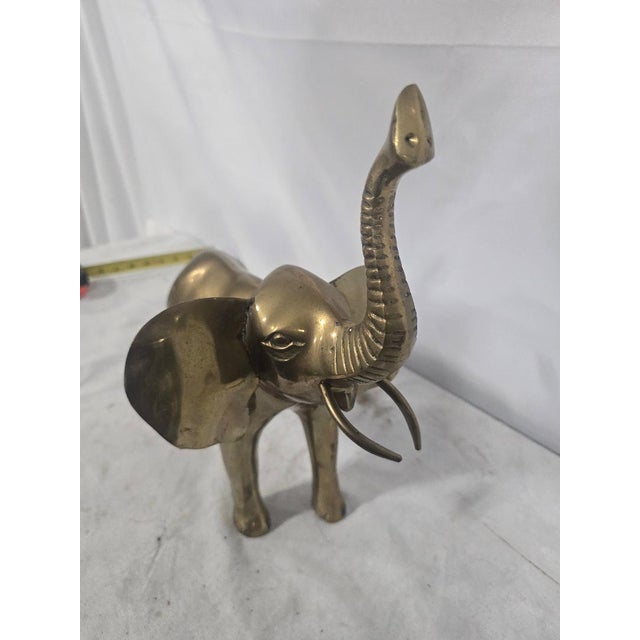 Vintage large brass elephant sculpture featuring a raised trunk, extended ears, curved tusks, and dimensional hand-...