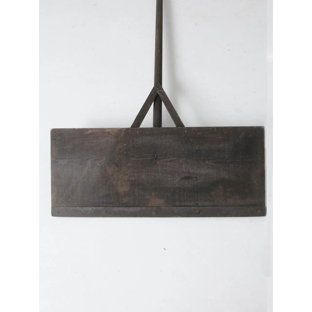 Antique primitive farm tool featuring a long wooden handle and flat-face shovel or spreader blade. The simple utilitarian...