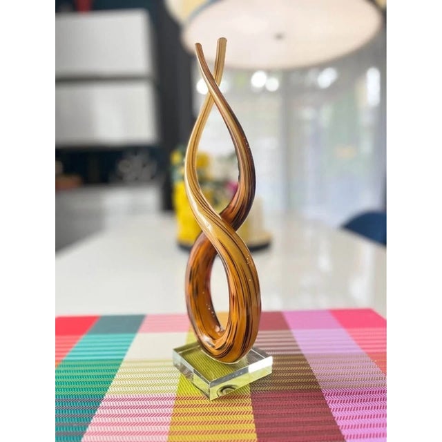 Striking vintage Murano-style art glass sculpture featuring an elegant "Love Knot" design in rich amber tones. Handcrafted...