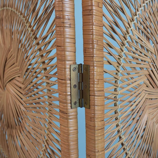 A three panel folding screen in buri rattan, each panel woven with three sunburst medallions that filter light...