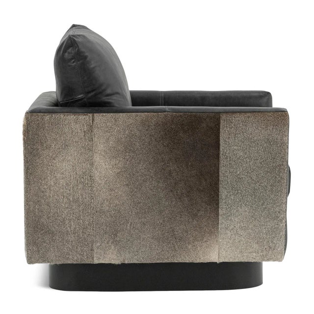 Striking arm chair upholstered with top grain black leather and natural hide accents. Each may vary in natural leather...