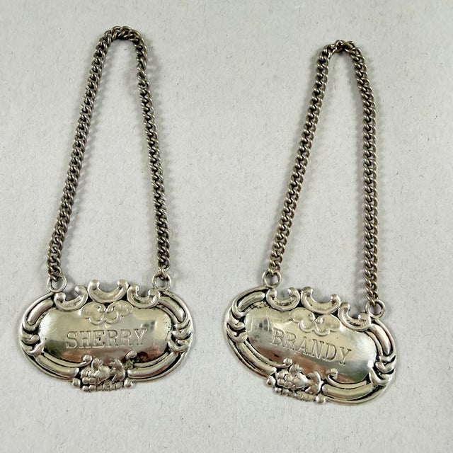 A pair of decanter liquor collar tags, Wallace Sterling, circa 1940s. Two similar tags, Sherry and Brandy, made to hang...