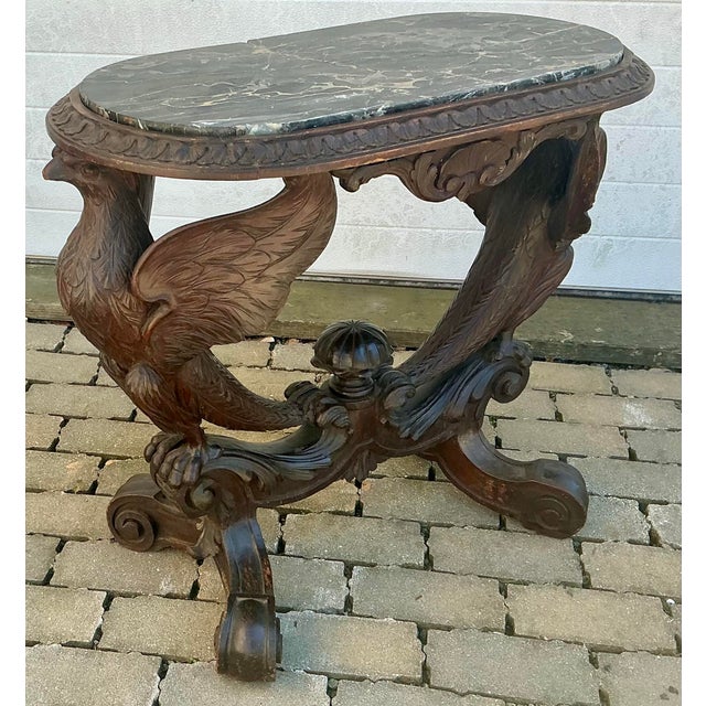 Incredible heavily carved walnut table. Two spread wing eagles perched on scrolled base with four feet. Black marble top....