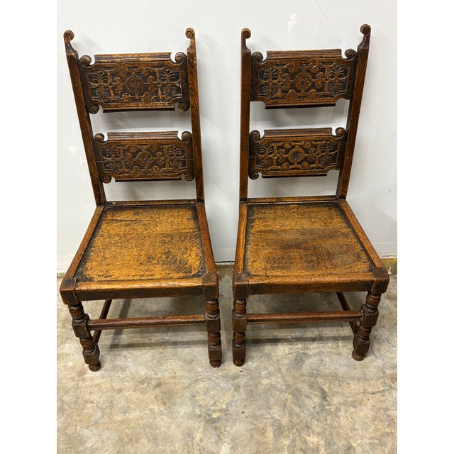 A handsome pair of antique English oak chairs, distinguished by their exceptional colour and surface, the wood having...