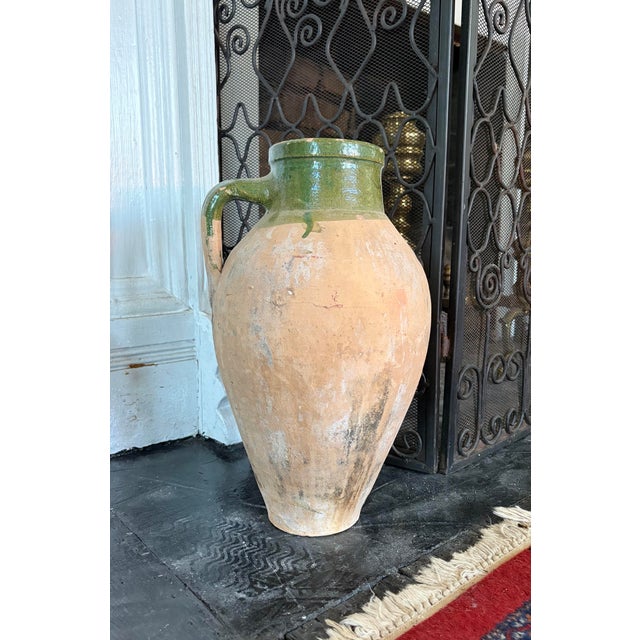 A beautifully time-worn terracotta vessel with a rich, organic presence and striking green glaze detail. The hand-thrown...