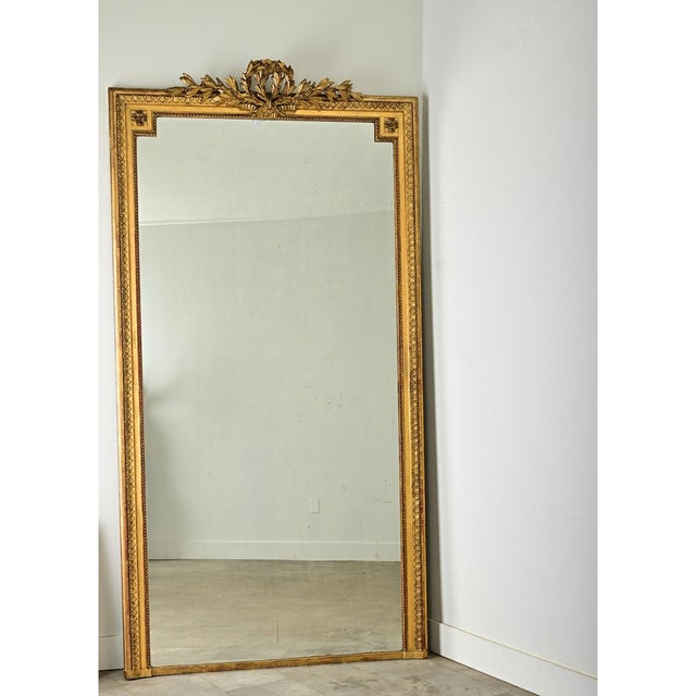 Dimensions: 99” H x 51” W x 4 ⅞” D A massive 19th century mantel mirror in the style of Louis XVI, with original mirror...