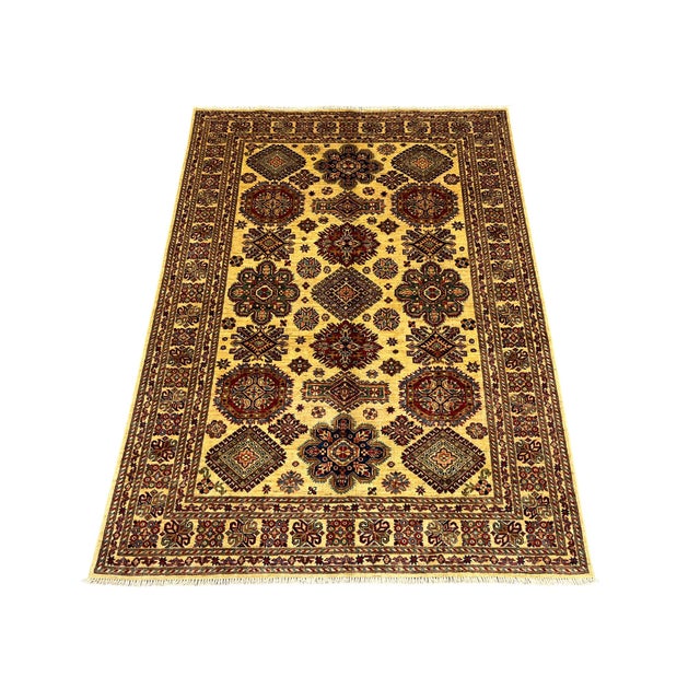 This Kazak style wool rug has a warm cream field filled with repeated tribal medallions in rust, navy, and brown. Smaller...