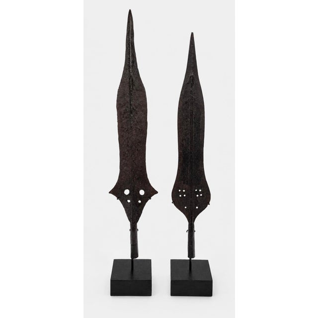 A striking pair of hand-forged African iron spearheads, presented as sculptural objects on custom hardwood display bases....