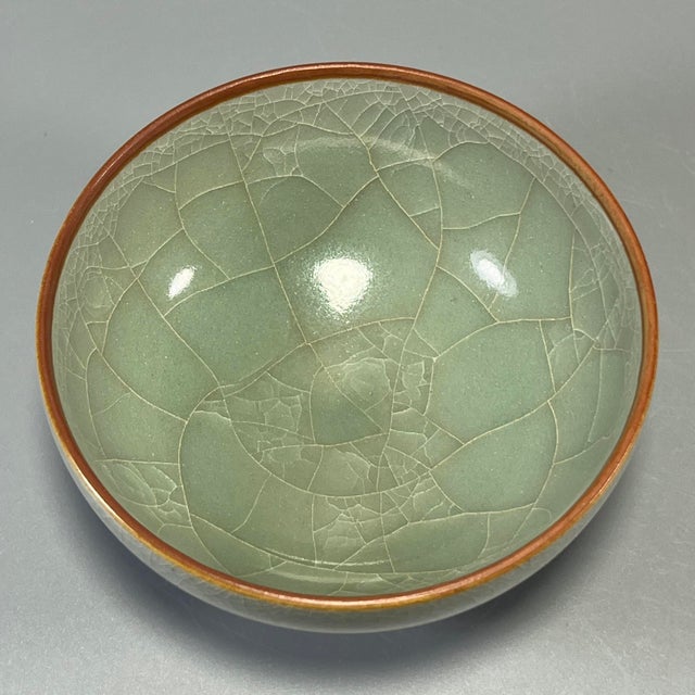 This vintage‑style celadon bowl features delicate natural crackled pale‑green glaze and an attractive brown‑toned rim....