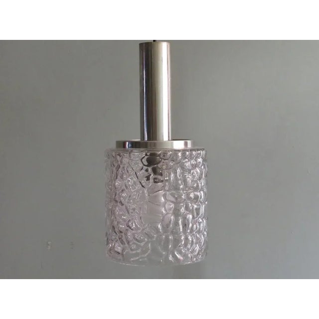 Pendant of thick, transparent relief glass with turtle motif. The suspension system is made of chrome-plated metal, as is...