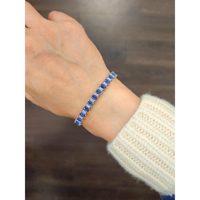 This exquisite bracelet showcases modern elegance. Featuring a series of natural emerald-cut blue Ceylon sapphires, each...