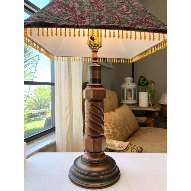 Elegant vintage table lamp featuring a substantial carved wood column with a distinctive spiral-carved detail and tiered...