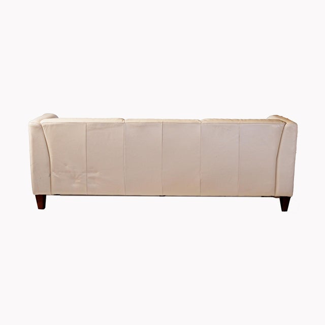 Alessia’ Italian leather sofa, off-white or cream with tufted details and dark stained squared wooden legs. Retailed by...