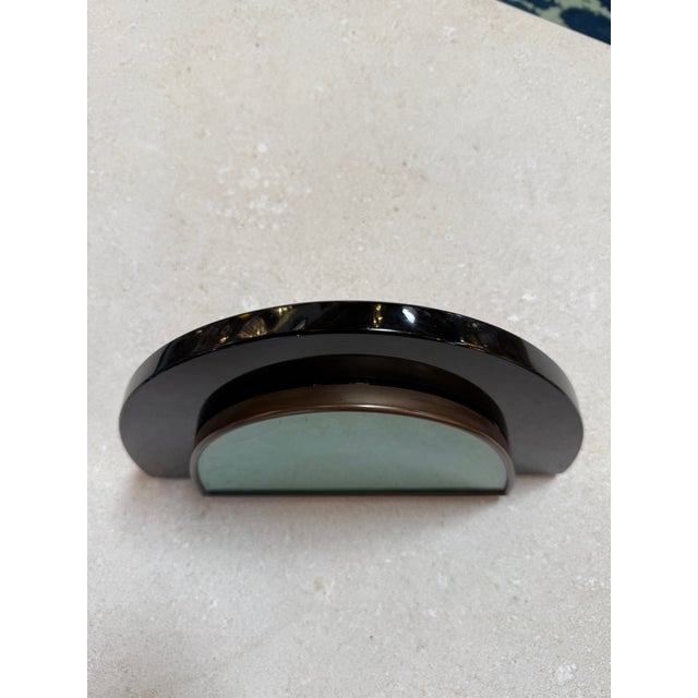 A sculptural Italian picture frame featuring a bold half-moon silhouette in glossy black lacquer, framing an arched glass...