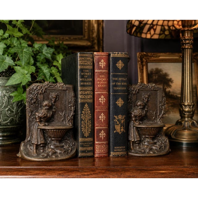 Charming vintage solid bronze bookends depicting a young maiden drinking from a decorative wall fountain, rendered in a...