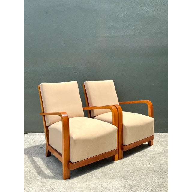 Distinguished by their sweeping modernist profiles, this pair of vintage Art Deco lounge chairs features elegantly curved...