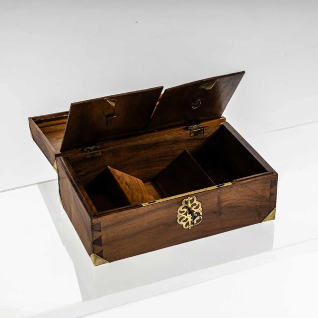 Rectangular walnut chest with brass fittings on the corners and a handle on the lid. The interior is divided into smaller...