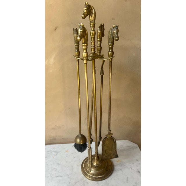 Mid century French brass fireplace set. with the shape of horse heads. The set includes the stand, a brush, poker, tongs,...