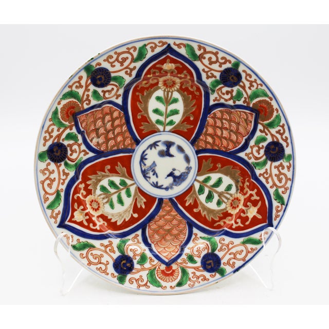 Circa 1860 pair of Imari plates, Japan. Boldly decorated rosette centers surrounded by scrolling floral tendrils, central...