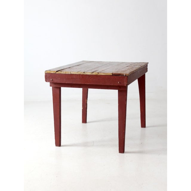 This rustic vintage farmhouse table features a slat wood top full of patina and character, paired with tapered legs in a...