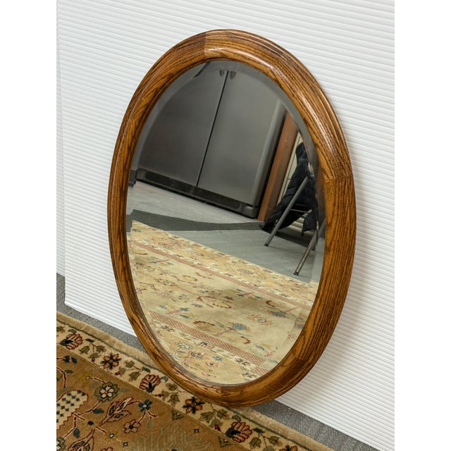 Design Plus Gallery presents a Late 20th Century Oak Wood Wall Mirror. The mirror has a beveled edge and is encased in a...