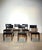 Elegant set of vintage dining chairs featuring dark wooden frames combined with black skai upholstery. The design is clean...