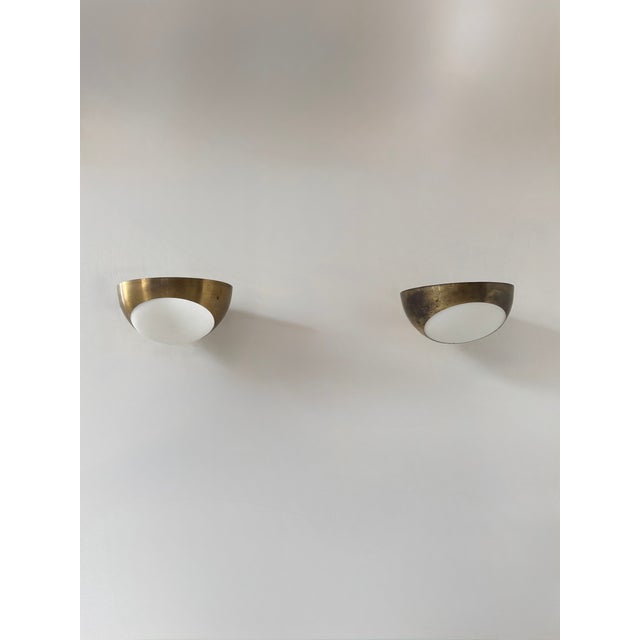 Pair of wall sconces produced in Italy in the 1960s, featuring a brass frame and a frosted opal glass diffuser. Two pairs...